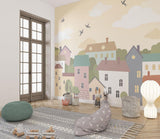 Village wallpaper mural featuring pastel houses shown in a bright modern nursery