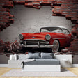 Vintage car wallpaper mural showcased in a modern living room, red classic car breaking through brick wall
