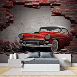 Vintage car wallpaper mural showcased in a modern living room, red classic car breaking through brick wall