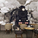 Vintage train wallpaper creating dramatic atmosphere in modern living room with dark furniture and high ceilings