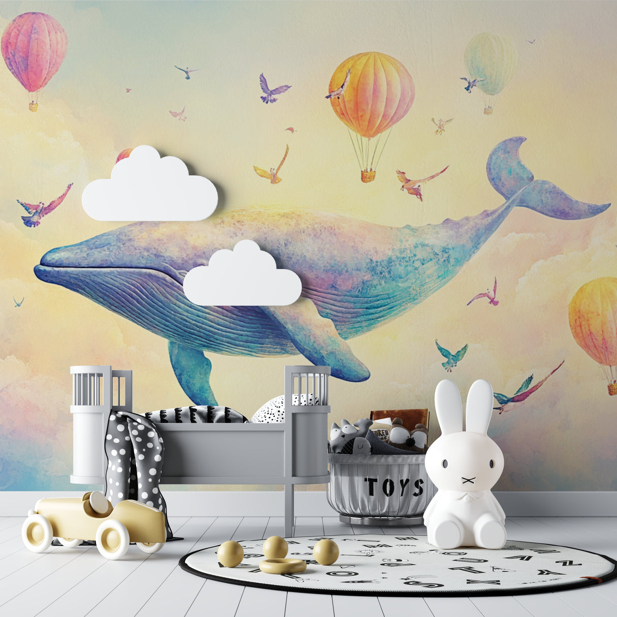 Baby room decorated with gentle whale and hot air balloon wall mural in soft pastel tones